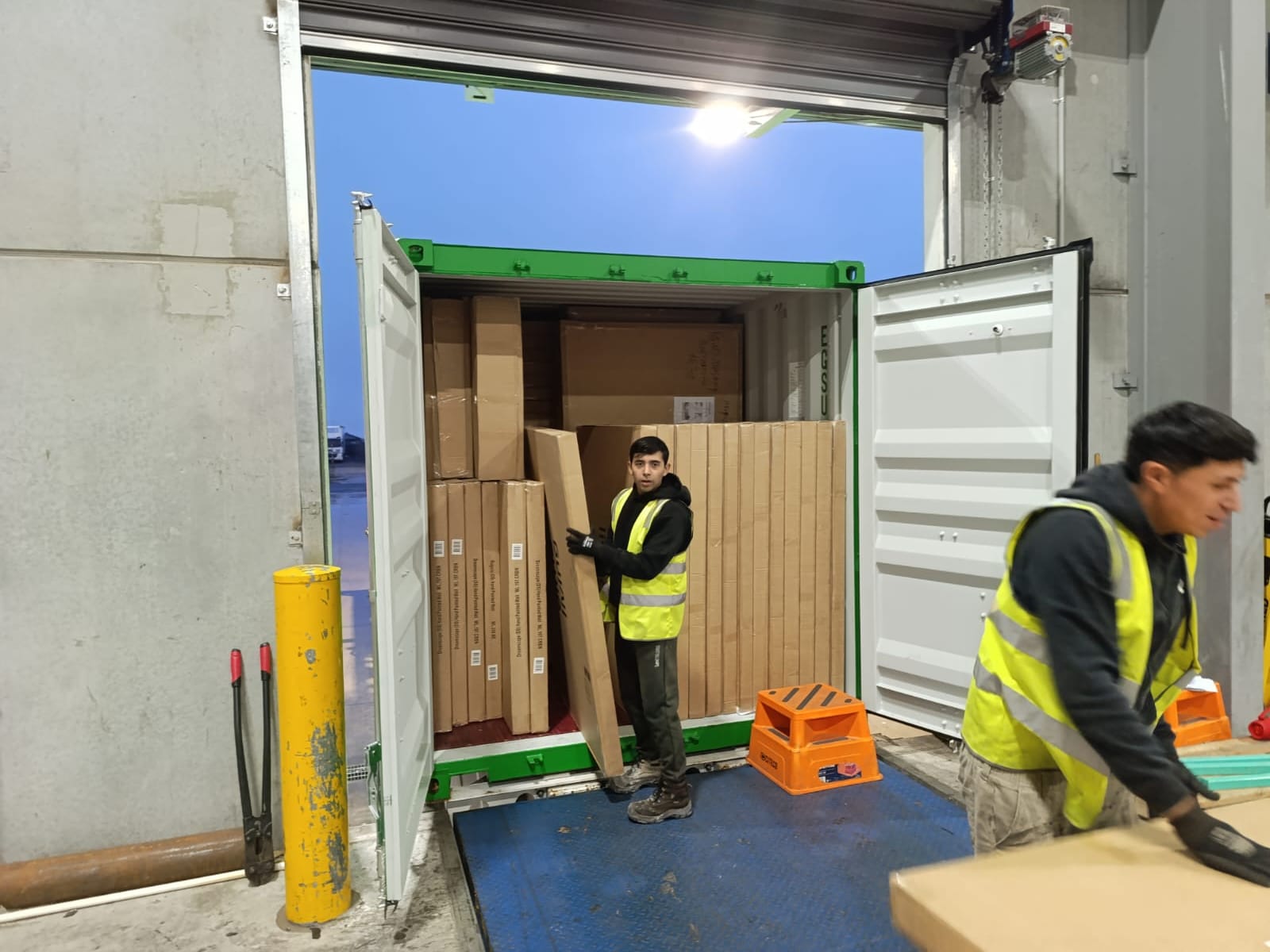 Calima worker unloading flat-pack cartons from a shipping container at the dock