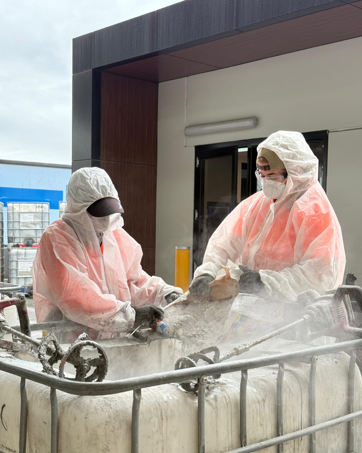 Two workers in full protective equipment on an industrial decant